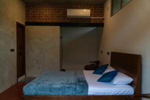 a bedroom with a large bed with blue pillows at Mango Orchards Two in Auroville