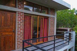 a brick house with a balcony and a wooden door at Mango Orchards Two in Auroville