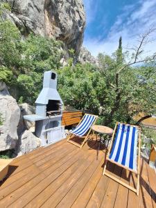 a wooden deck with two chairs and a stove at Spacious Mobile Home "House Lena" for 7 in Eurocamp Rača - Sea View & Private terrace in Sveti Juraj