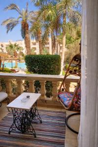 a patio with a table and a chair and palm trees at Casa Dòdò - Sunny Lakes Compound in Sharm El Sheikh