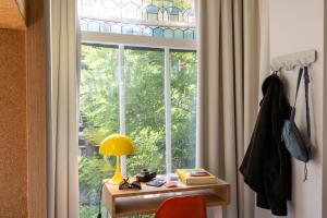 a window with a desk with a lamp and a table with a lamp at Hotel BonBon & BonBon Budget in Rotterdam