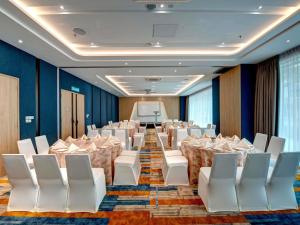 a banquet hall with white chairs and tables and a screen at ibis Styles Johor Iskandar Puteri in Johor Bahru