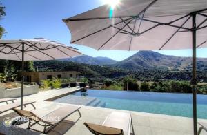 a swimming pool with two chairs and an umbrella at Casa s - lilina in Tralonca