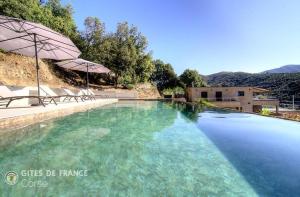 a large swimming pool with chairs and an umbrella at Casa s - lilina in Tralonca