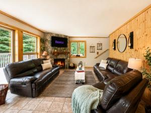 a living room with a leather couch and a fireplace at Riverwood Lodge in Leavenworth