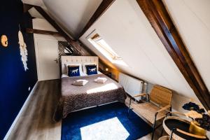 a small attic bedroom with a bed and a chair at bijDorien in Gennep