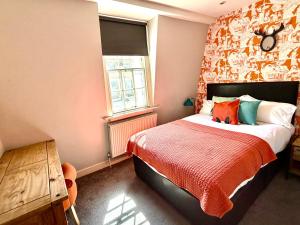 a bedroom with a bed with a red blanket at Dream Stays Bath - Trim Street Townhouse with Hot tub in Bath