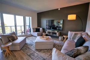 a living room with two couches and a tv at 211 - Bright Condo - Pool and Cozy Atmosphere in Baie-Saint-Paul