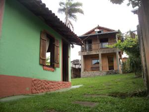 a green building with a palm tree in the background at Pousada Beija-Flor in Lavras Novas