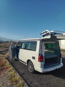 a white van with its door open with a surfboard on top at Nomad Campers VW California in La Mareta