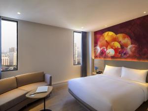 a hotel room with a bed and a couch at ibis Styles Bangkok Ratchada in Bangkok