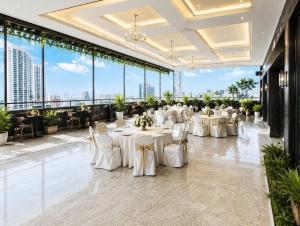 a banquet hall with white tables and chairs and large windows at Hotel Eco Park By Carlton Suites in kolkata