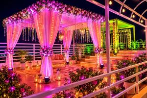 a wedding venue with pink curtains and purple flowers at Hotel Eco Park By Carlton Suites in kolkata +87 photos