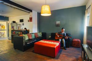 a man sitting on a couch playing a guitar in a living room at Go Hostel in Córdoba