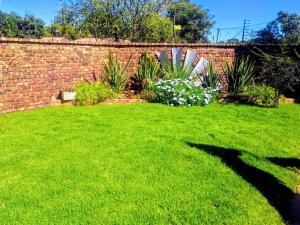 a yard with green grass and a brick wall at Schweizer Lodge in Schweizer-Reineke +5 photos