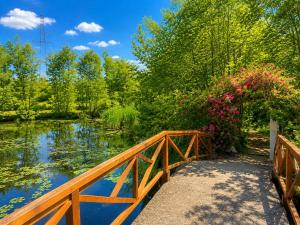 a wooden bridge over a river with trees and flowers at Bujtinat te Mullari in Laç