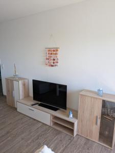 a living room with a flat screen tv on a wooden entertainment center at Ferienwohnung nahe Nordseeküste in Großheide