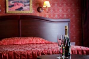 a bottle of wine and two glasses on a table in a bedroom at Viešbutis "Linelis" in Paplatelė