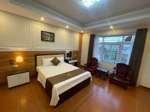 a bedroom with a bed and two chairs and a window at G9 Home hotel in Hanoi