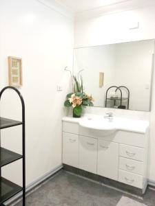 a bathroom with a white sink and a mirror at Lush & Co Auckland Bed & Breakfast in Auckland