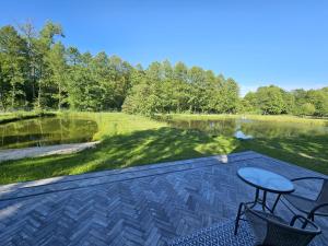 a patio with a table and chairs next to a lake at STAW się tu in Młyny +10 photos