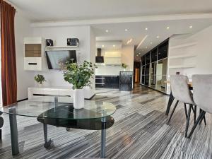 a living room with a glass table and a kitchen at Apartament SPACE & SUN z wewnętrzym ogrodzonym parkingiem in Toruń