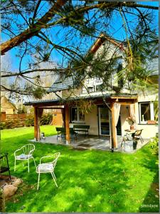 a house with a patio and chairs in the yard at Malanówka II Radęcin in Radęcin