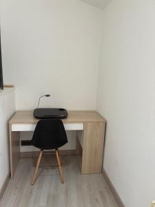 a desk with a black chair next to a white wall at Casa Vidán completa Santiago Rural in Santiago de Compostela +2 photos