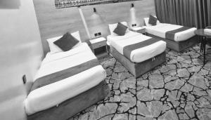 three beds in a room with rocks andphaltysical at فندق ميراب الروضة in Al Khansāk