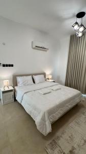 a white bedroom with a large bed and two lamps at The Inn Salalah in Salalah