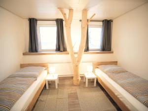 two beds in a room with two windows at Albsteig-Apartments Gruibingen in Gruibingen