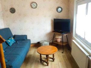 a living room with a blue couch and a tv at gite 618 in Helfaut