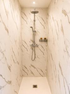 a bathroom with a shower with white marble walls at Gîte Caussenard rénové in Le Massegros +8 photos
