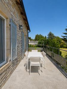 a table and chairs on the balcony of a house at Gîte Caussenard rénové in Le Massegros
