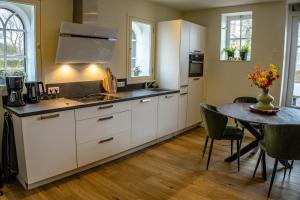 a kitchen with white cabinets and a table with a dining room at BrinkZicht vakantieverblijf in Peize