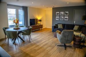 a living room with a couch and a table with chairs at BrinkZicht vakantieverblijf in Peize