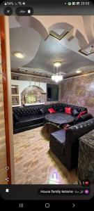 a living room with a black leather couch at Maison hôte ketama in Tlata Ketama