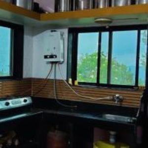 a kitchen with windows and a counter with a stove at Hotel Green lotus villa mahabaleshwar in Mahabaleshwar