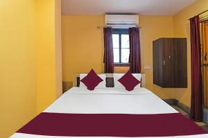 a bedroom with a large bed with red pillows at Hotel Ashirbad I comfort Near Railway Station in Bhubaneshwar