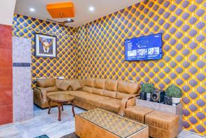 a living room with a couch and a tv on a wall at Hotel Ashirbad I comfort Near Railway Station in Bhubaneshwar