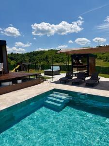 a swimming pool with chairs and a table and an umbrella at Rent a NEST in Arandelovac