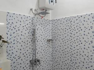 a shower in a bathroom with black and white tiles at Ella Green Cottages in Ella