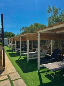 a row of chaise lounges and chairs under a pavilion at CH Guest House in Vernole