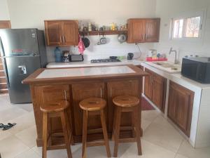a kitchen with wooden cabinets and a kitchen island with stools at Maison villa la faveur in Ngaparou