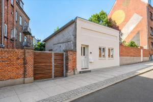 a brick building on a street with a fence at Det Gamle Vaskeri - Historical Apartment in Horsens in Horsens