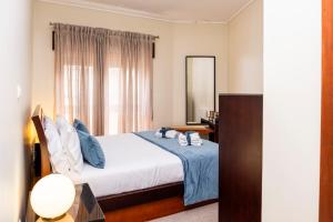 a bedroom with a bed with blue sheets and a mirror at RH Charming Apartment - D Nuno in Barcelos