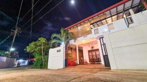 a white house with a palm tree in front of it at Weligama Bay House in Weligama