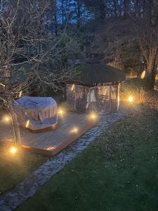 a gazebo with lights in a yard at night at POGO dom nad Narwią - 4 sypialnie, duża sauna, balia, pomost, plac zabaw in Pogorzelec
