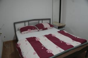 ein Bett mit roten und weißen Decken und Kissen in der Unterkunft Kod Hamde in Jajce