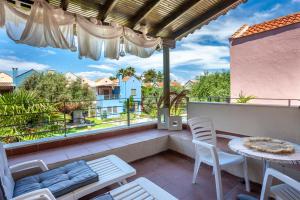 a patio with a table and chairs on a balcony at Villa Portoblue Pearl in Pefkochori +31 photos